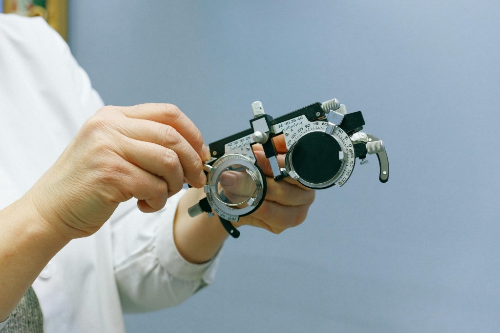 Close-up of hands adjusting an optical trial frame against a blue background, emphasizing precision and professionalism.
