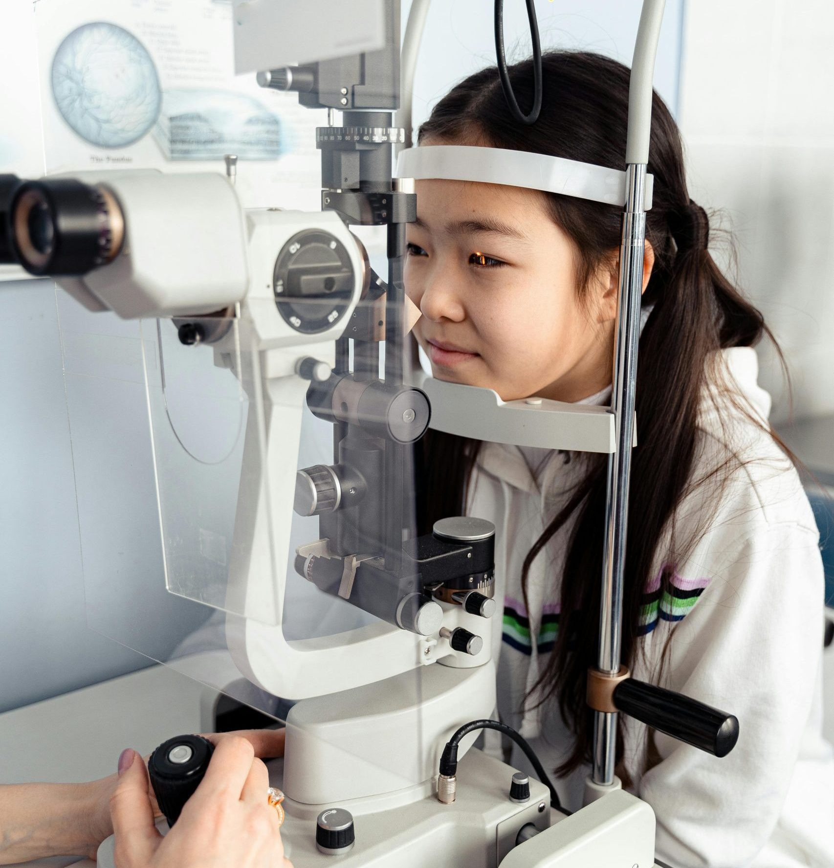 A teenage girl at an eye clinic examining her vision with optical equipment.