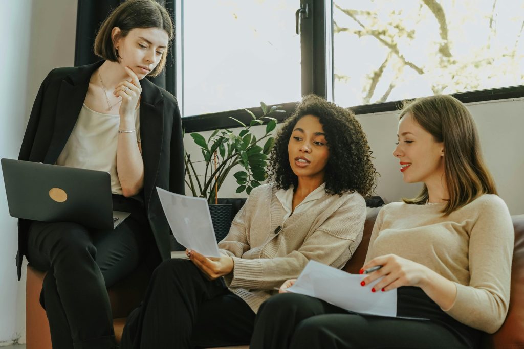 Three professional women engaged in a collaborative meeting in a modern office setting.