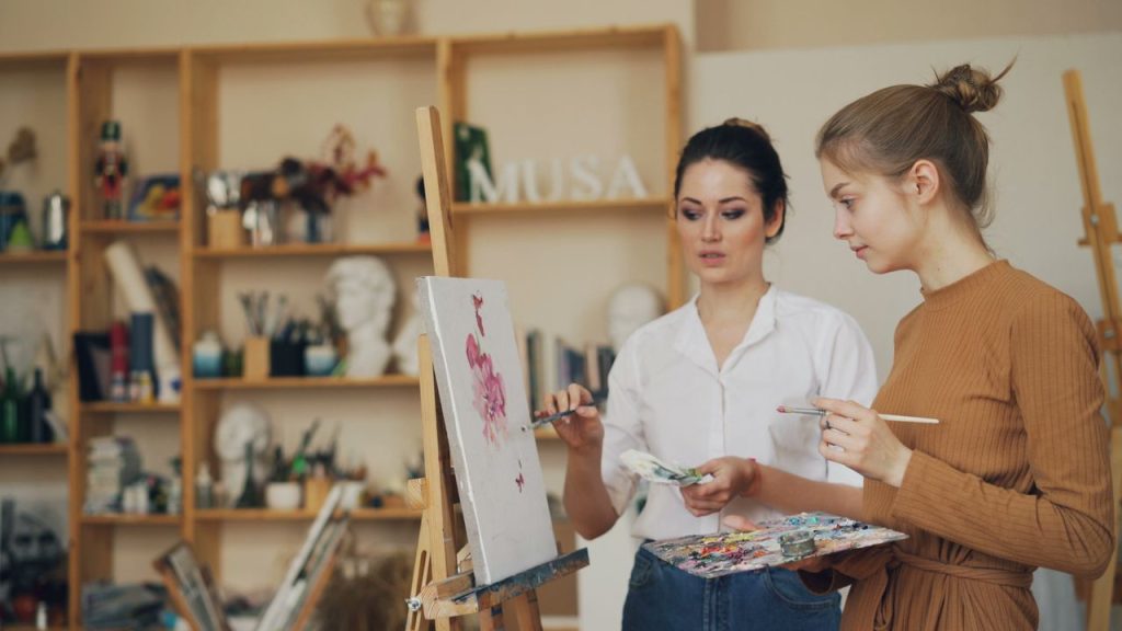 Two women engaged in creating art on canvas in a cozy studio setting.