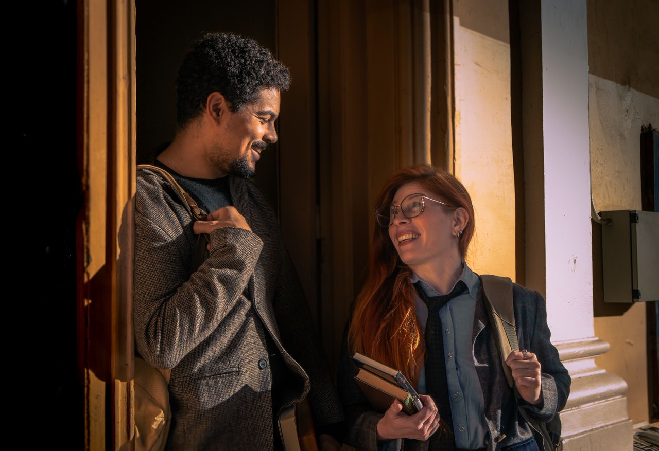 Two adults, a man and woman, smiling and talking near a doorway.