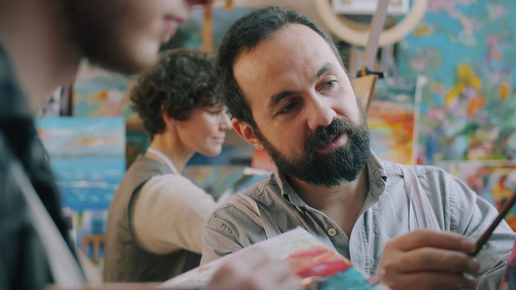 An art teacher guides students in a vibrant studio setting.